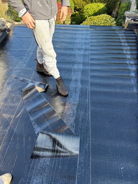 Storm Dry Roofing flat roof job: new black felt base layer being rolled out across the deck
