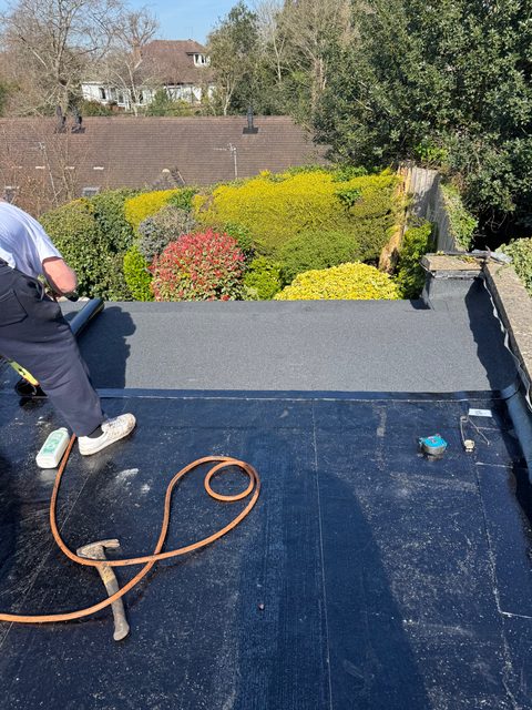Storm Dry Roofing flat roof job: grey mineral cap sheet being torched on over the black base layer