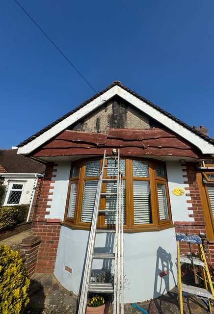 Storm Dry Roofing gable cladding job, before: old timber cladding failing on a bungalow gable above a bay window