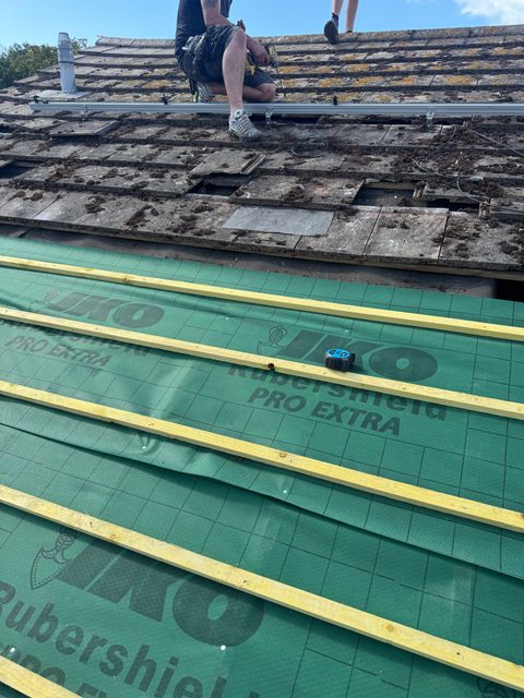 Storm Dry Roofing re-roof: new green breathable membrane and yellow battens laid below the old tiles still to be stripped