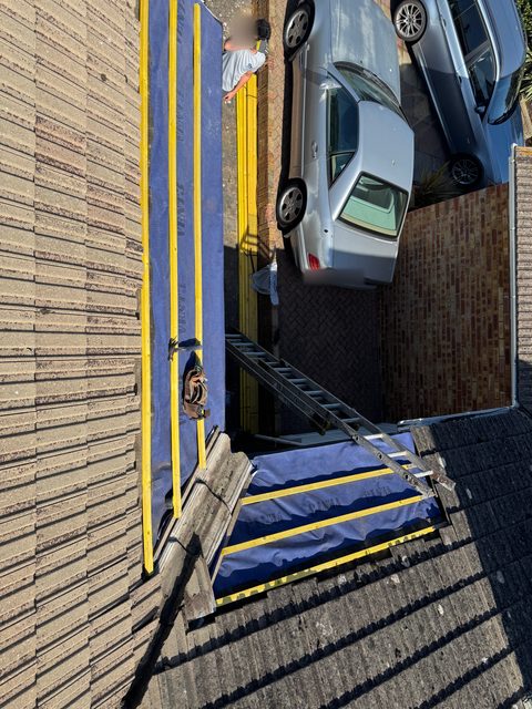 Storm Dry Roofing re-roof seen from above: new blue breathable membrane and yellow battens running down the roof, with a ladder to the scaffold