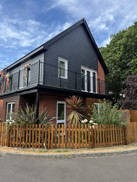 Storm Dry Roofing: grey tile-hung gable and pitched roof on a brick corner house with a balcony