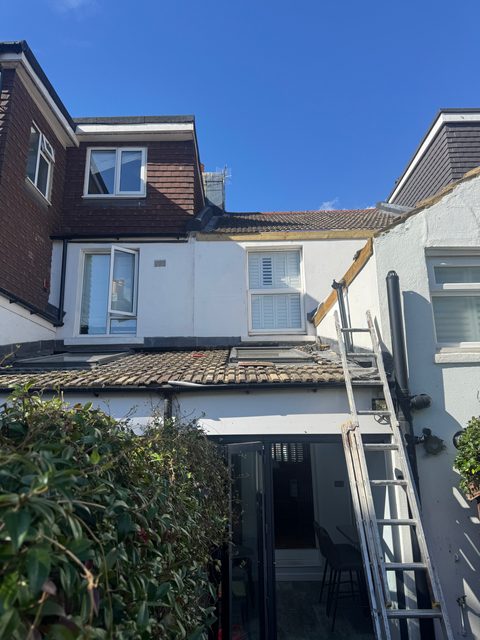 Storm Dry Roofing: ladder up at the back of a terrace for fascia and gutter work on the roofline