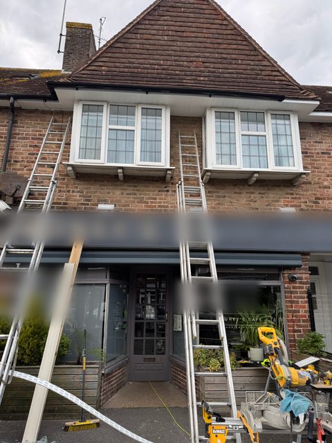 Storm Dry Roofing roofline job above a shopfront later the same day, with two ladders up along the front