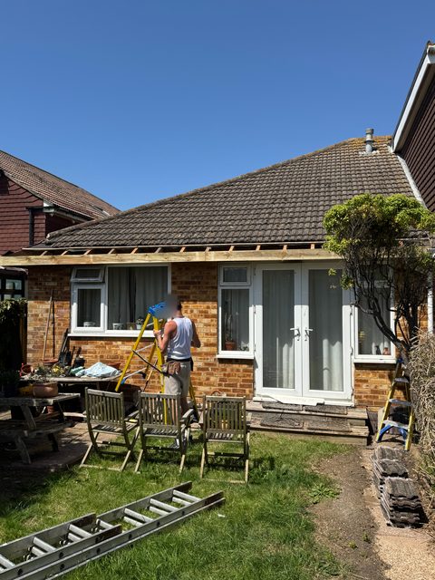 Storm Dry Roofing fascia job: stepladder up to the stripped eaves of a bungalow while the old boards come off