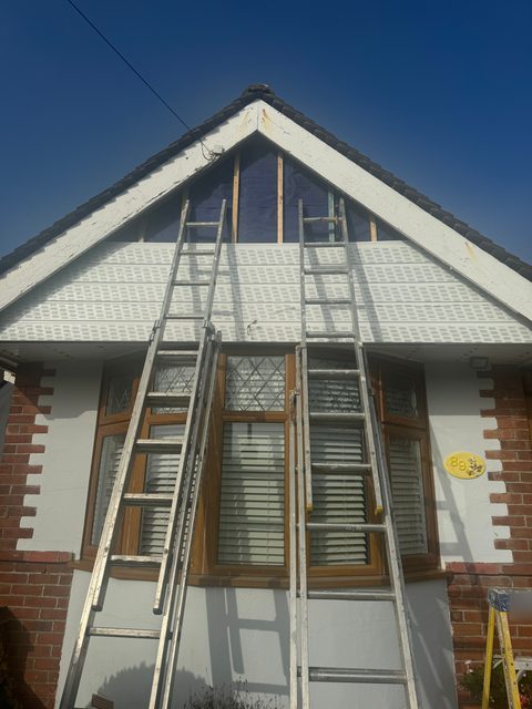 Storm Dry Roofing gable cladding in progress: new white uPVC going on the gable, with ladders up